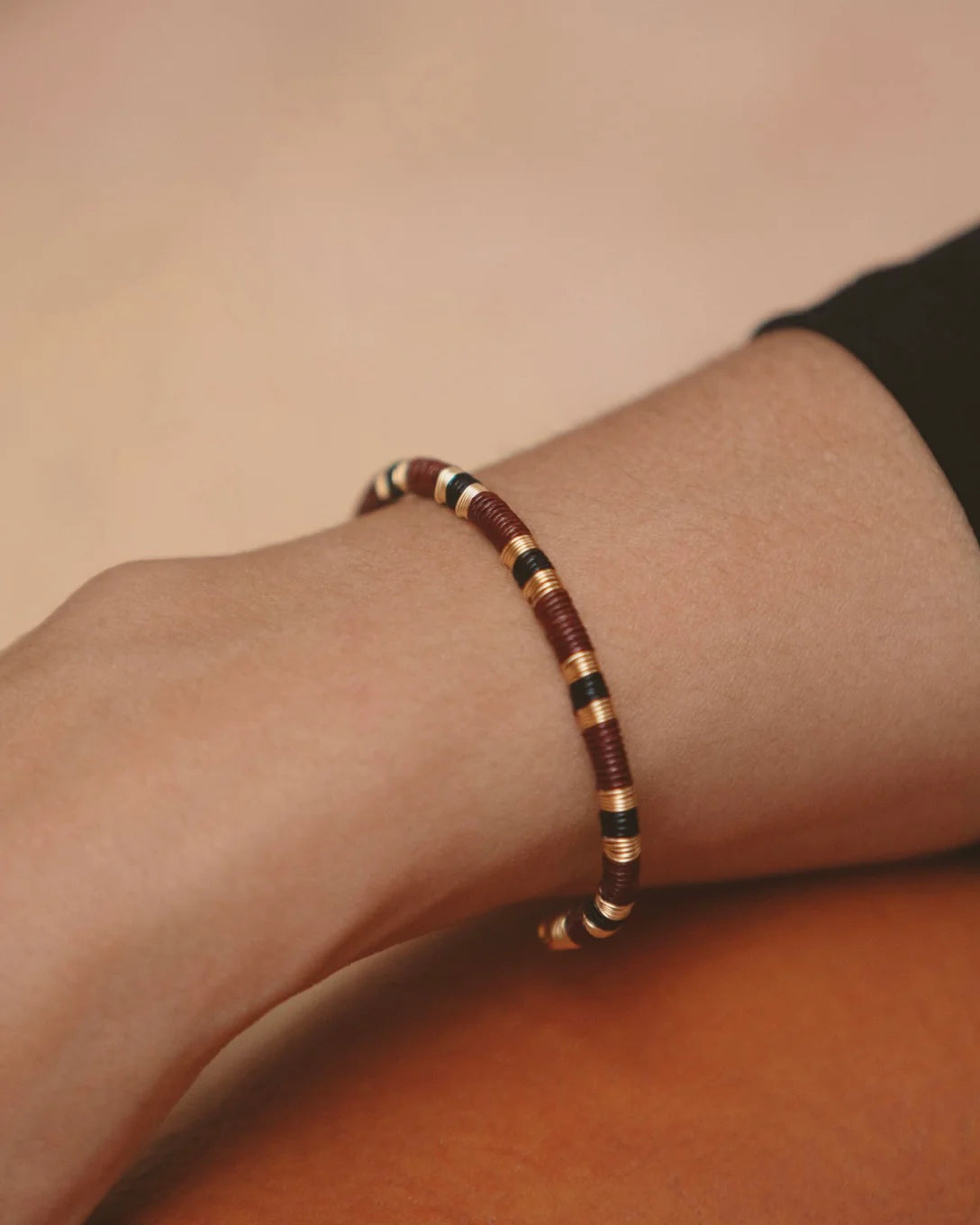 Bamboleira terracotta black and gold striped bangle shown on model's wrist