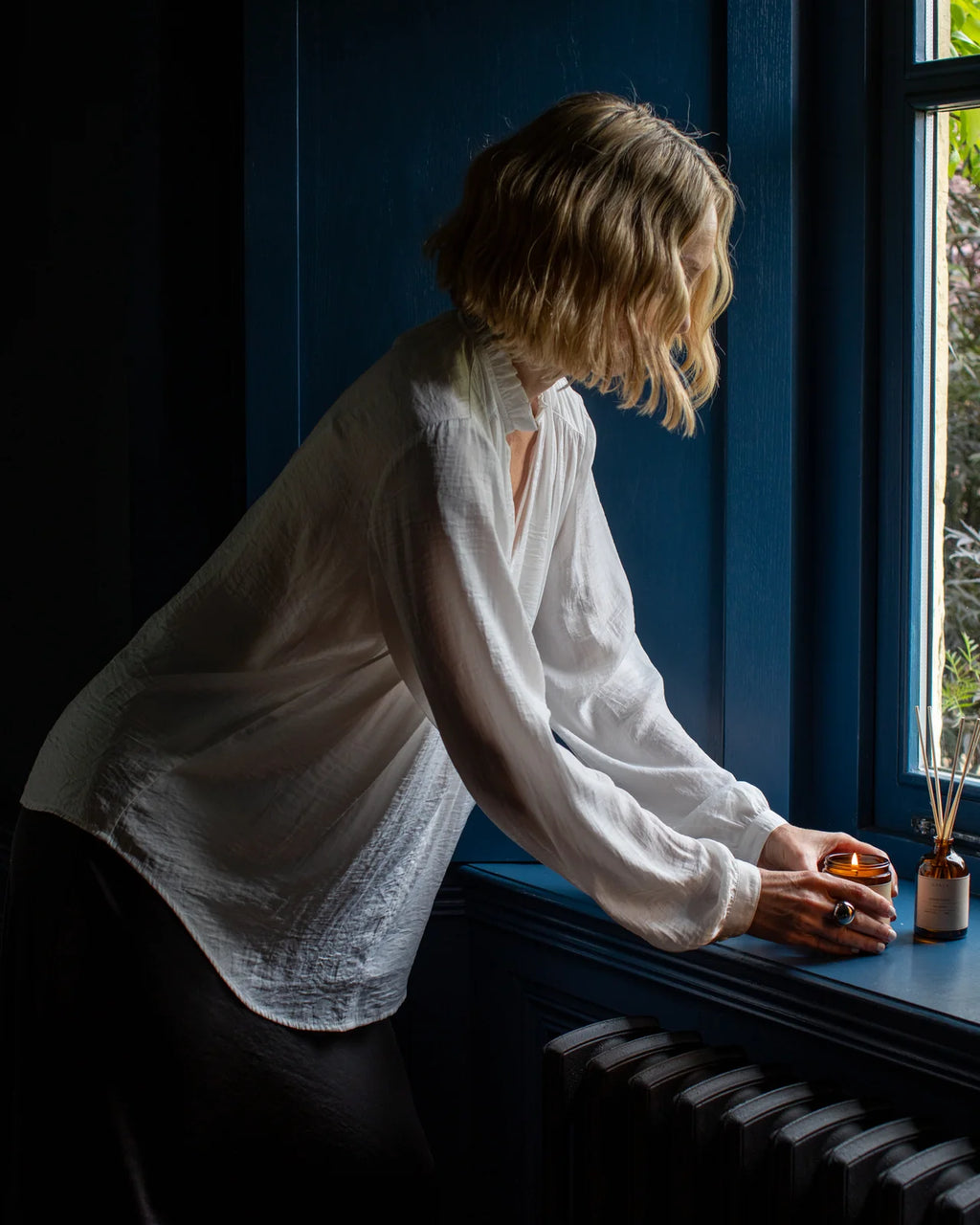 Women’s relaxed fit shirt with pearl button cuffs worm by woman lighting candle in window