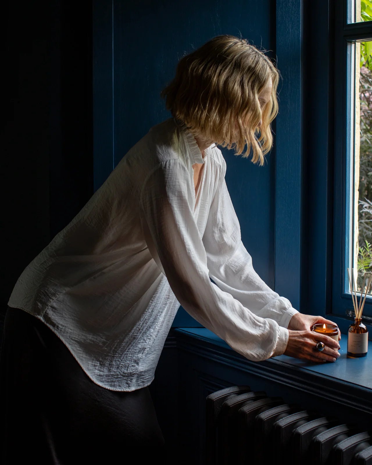Women’s relaxed fit shirt with pearl button cuffs worm by woman lighting candle in window