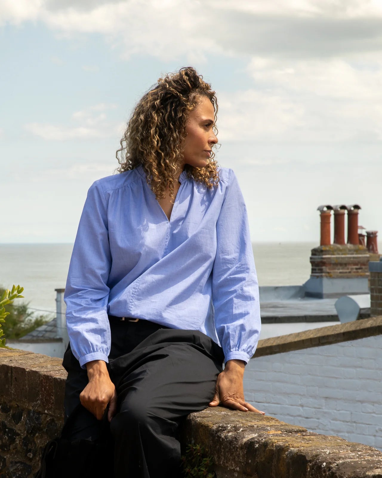 Chalk Melody chambray cotton blouse with gathered shoulders worn by woman looking over rooftops

