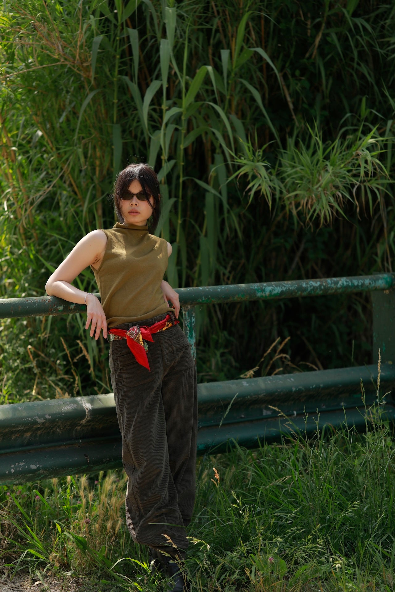 woman leaning on fence wearing Orfeo khaki wide-leg cotton trousers with patch pockets