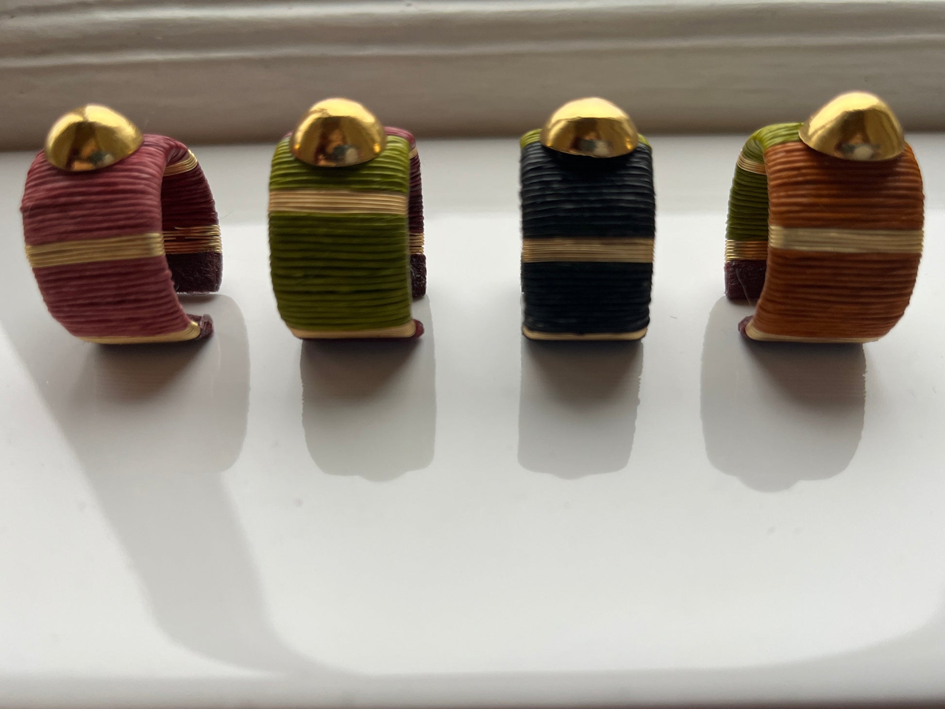 Four striped rings with gold tops on a white surface