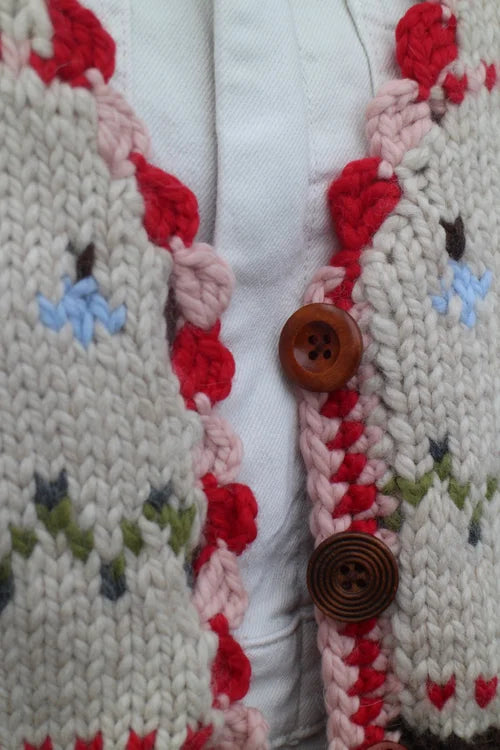 Close-up of hand-knitted Nicky Dupont waistcoat with wooden buttons and scalloped edges