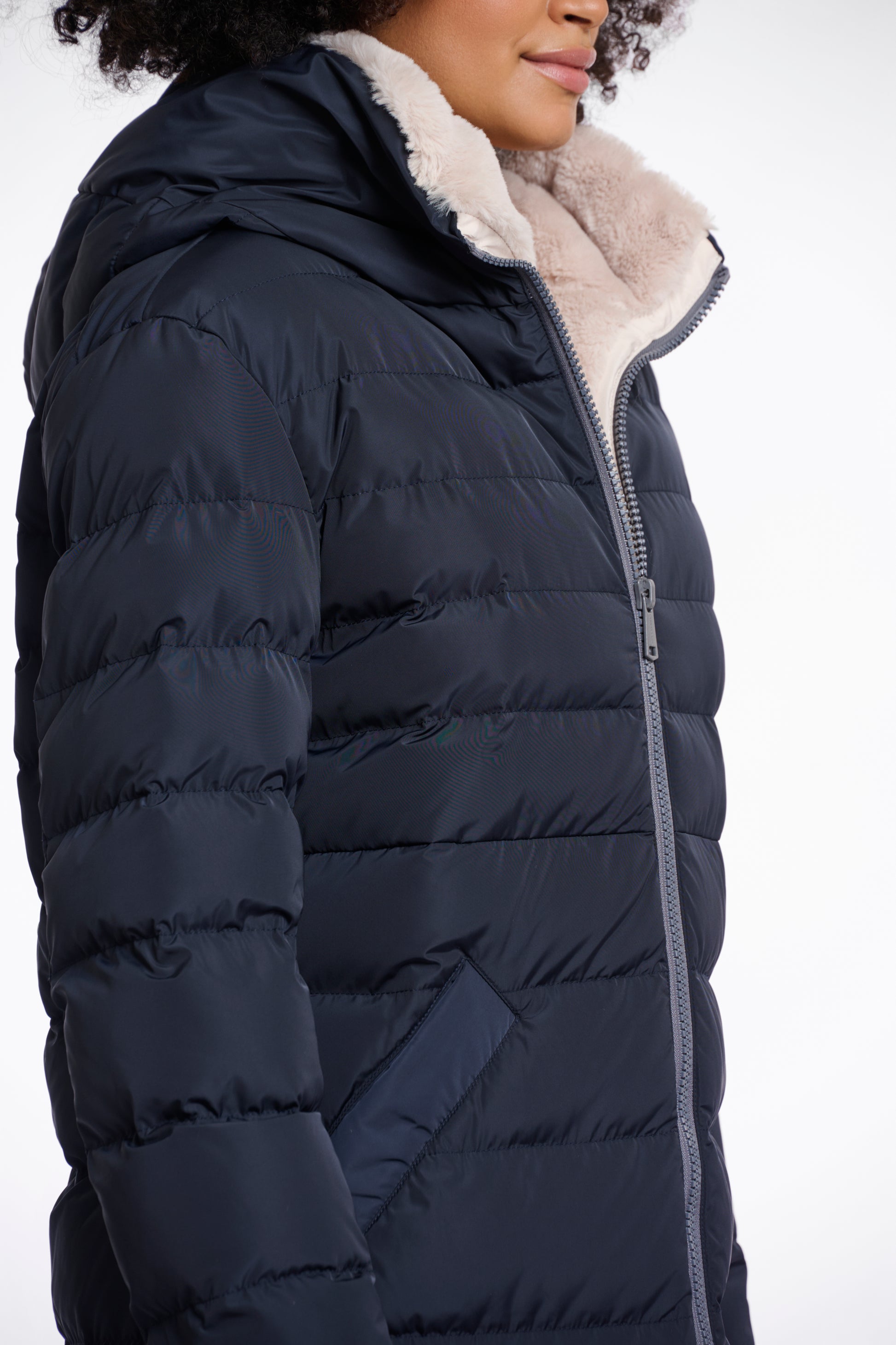 Warm puffa coat with snap button pockets and hooded collar. close up image with faux fur interior showing