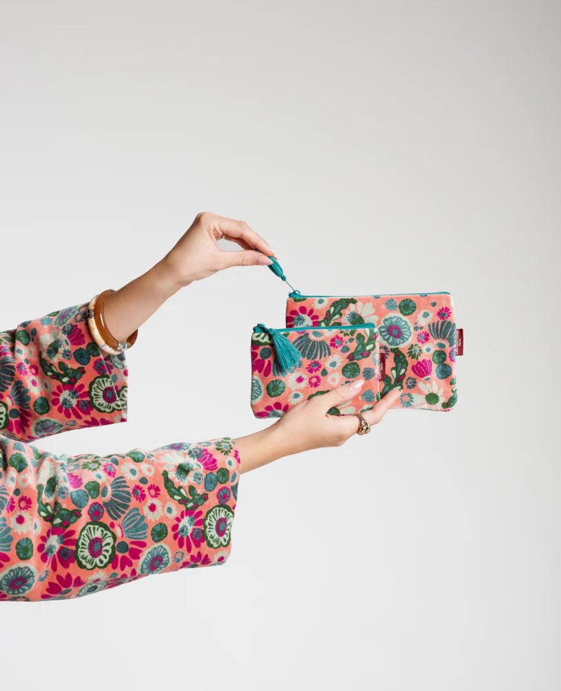 Person wearing a floral outfit holding matching small and medium pouches in velvet