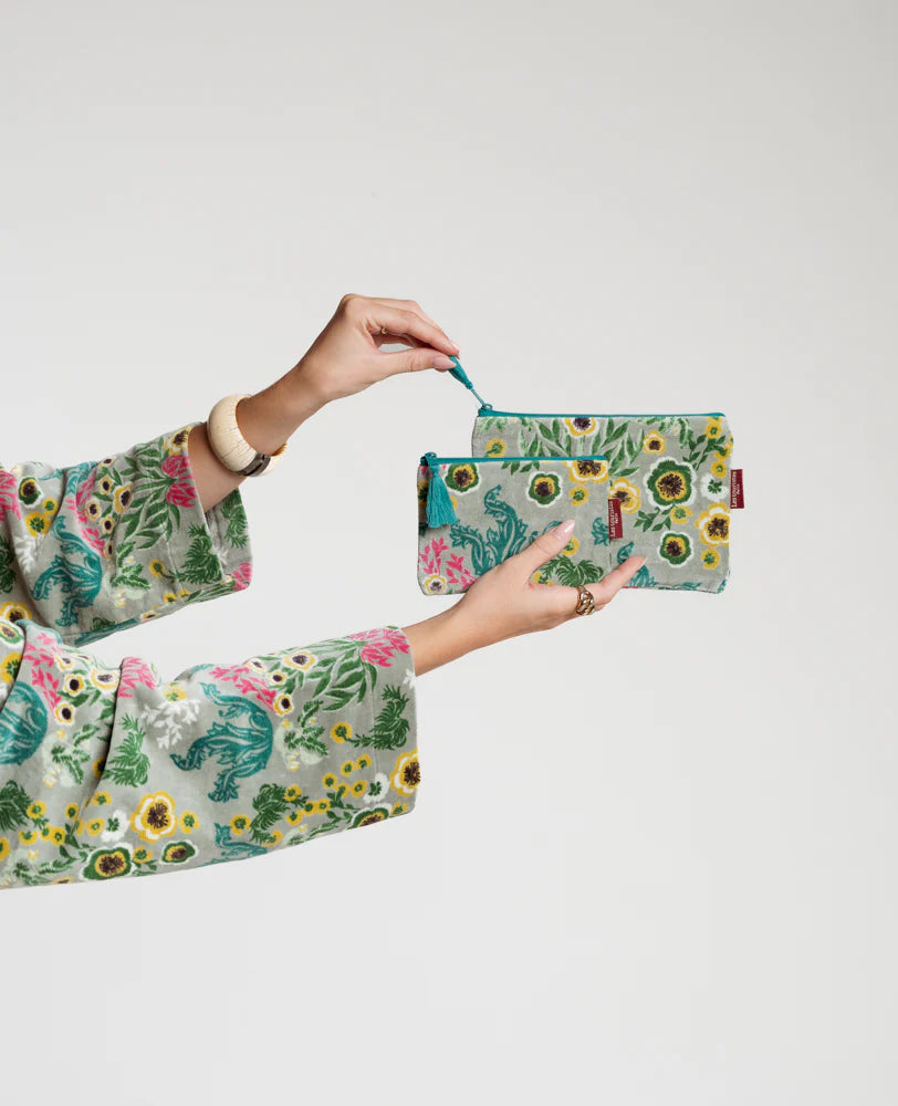 Person holding a velvet floral-patterned pouch with a matching bag 
