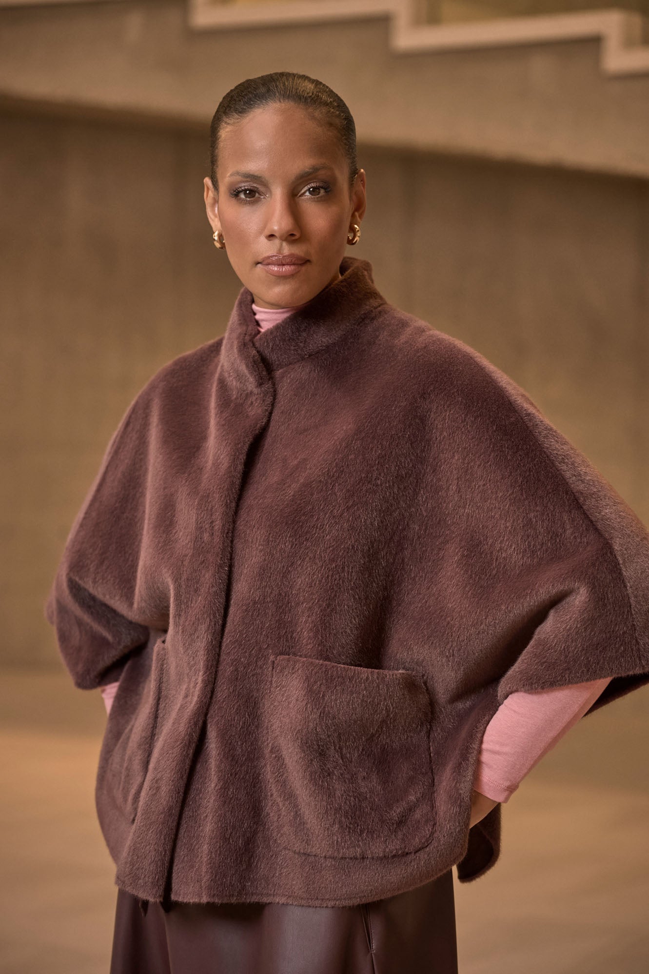 Chocolate Bean faux fur cape with snap closure worn by model with hands in pockets