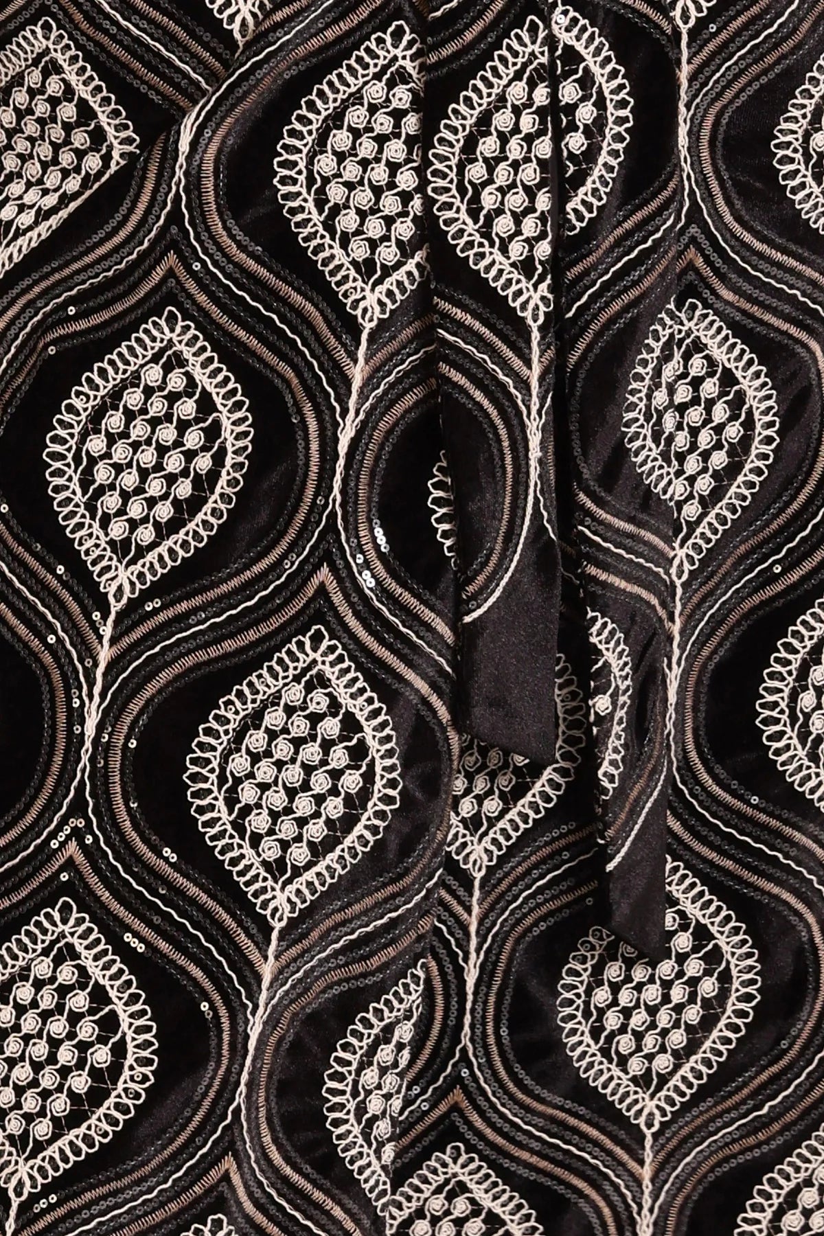 Close-up of the cotton embroidered fabric with decorative elements on a dark background