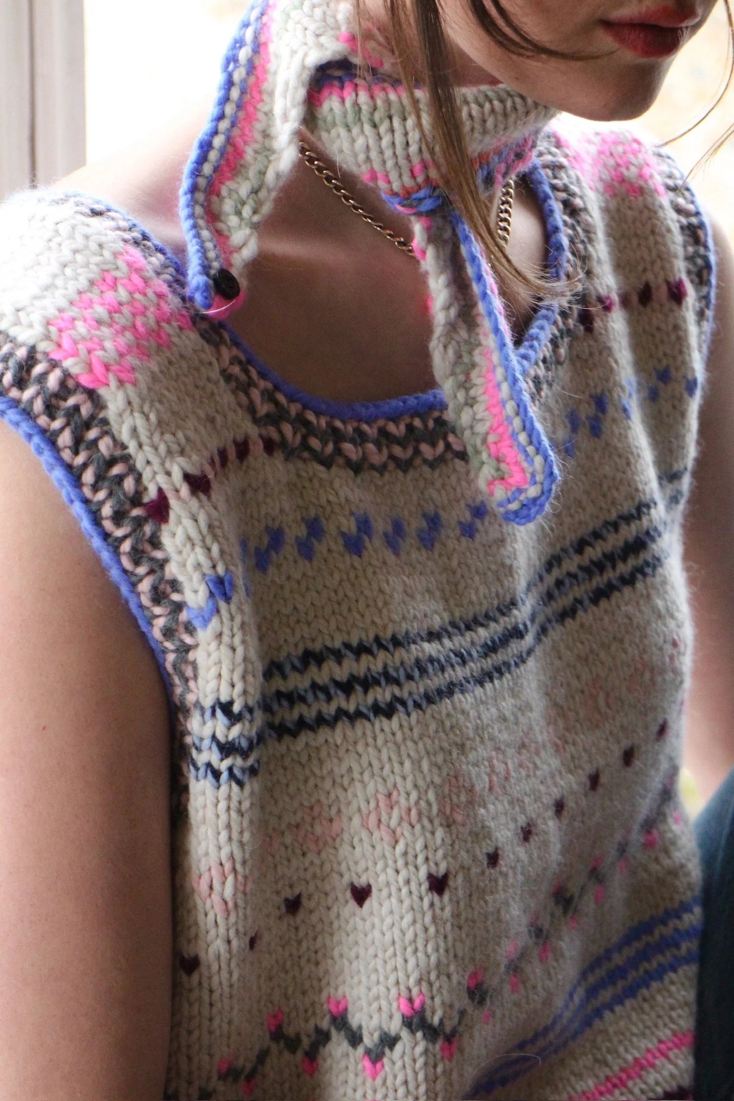 Girl wearing a Nicky Dupont hand knit patterned  vest with colorful accents and scarf