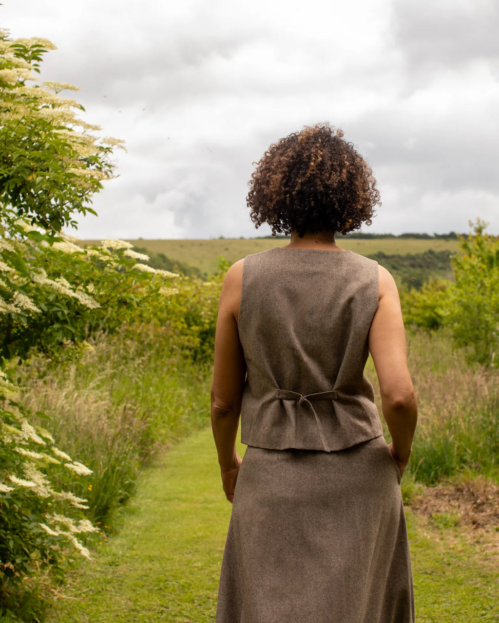 Classic wool blend waistcoat for layering shown from behind and with skirt 
