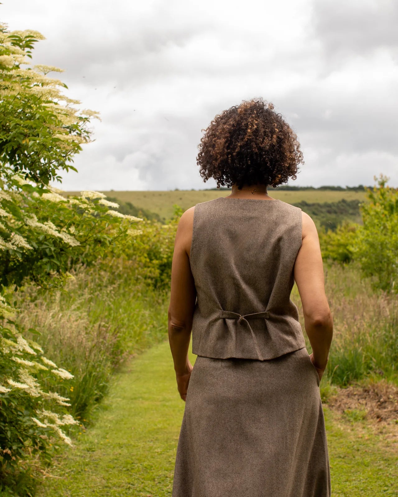 Classic wool blend waistcoat for layering shown from behind and with skirt 
